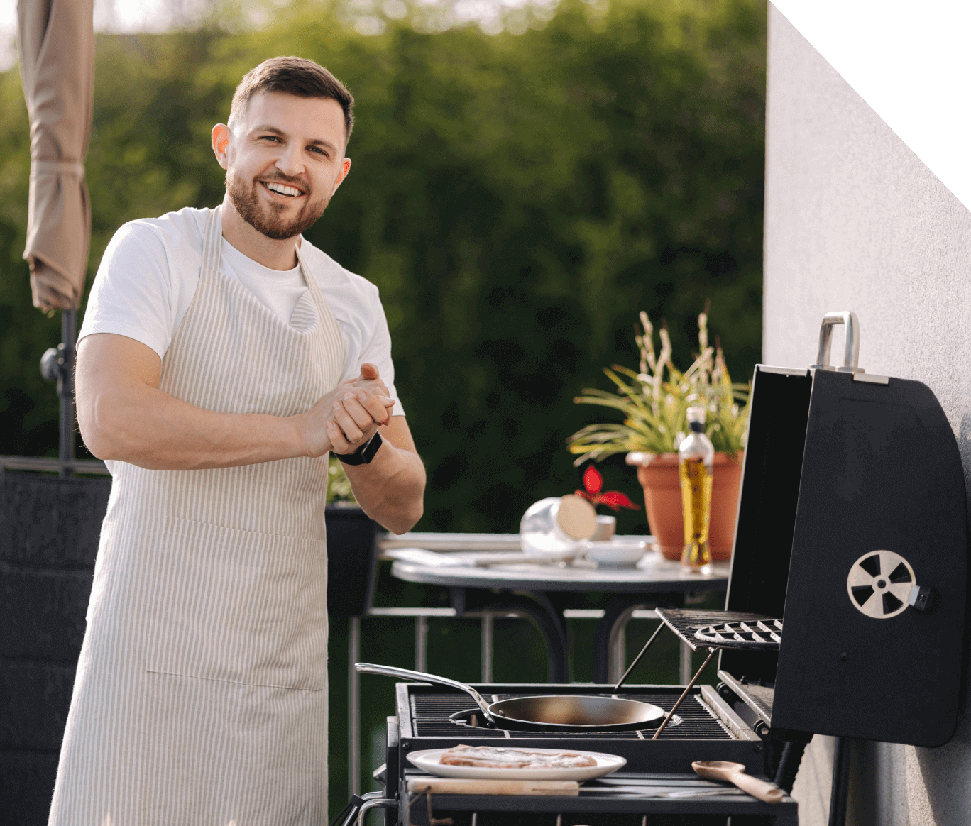 Man smiling while grilling outdoors.